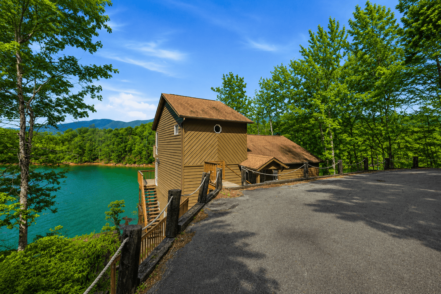 The parking area and driveway alongside the house, with the lake immediately below the rope fence.