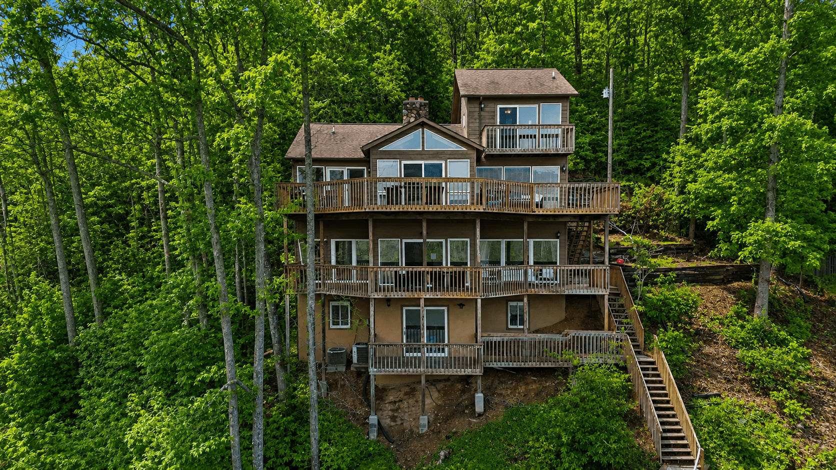 The lake side of the house, showing all four deck levels stacked down the slope and the exterior stair run.